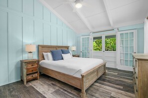 Un dormitorio con cama de madera, dos mesitas de noche, un tocador y un aparador.