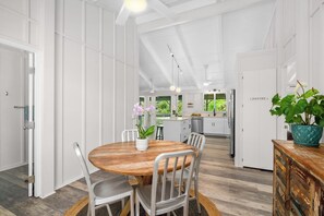 Una cocina moderna con armarios blancos, una mesa de comedor de madera y una planta en maceta.