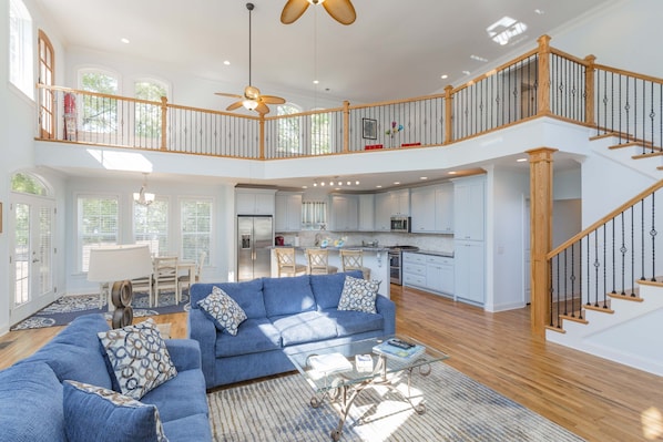 A spacious living area with a blue sofa, a glass coffee table, and a staircase leading to a second floor. - Nashville Old Hickory Lake Home on Old Hickory Lake (Mt Juliet)