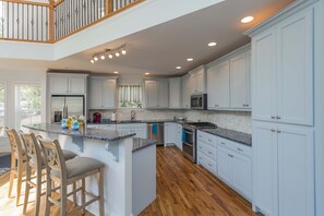 A spacious kitchen with white cabinets, a central island with bar stools, and a wooden floor. - Nashville Old Hickory Lake Home on Old Hickory Lake (Mt Juliet)
