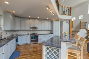 A kitchen with white cabinets, a granite countertop, and a wooden staircase. - Nashville Old Hickory Lake Home on Old Hickory Lake (Mt Juliet)