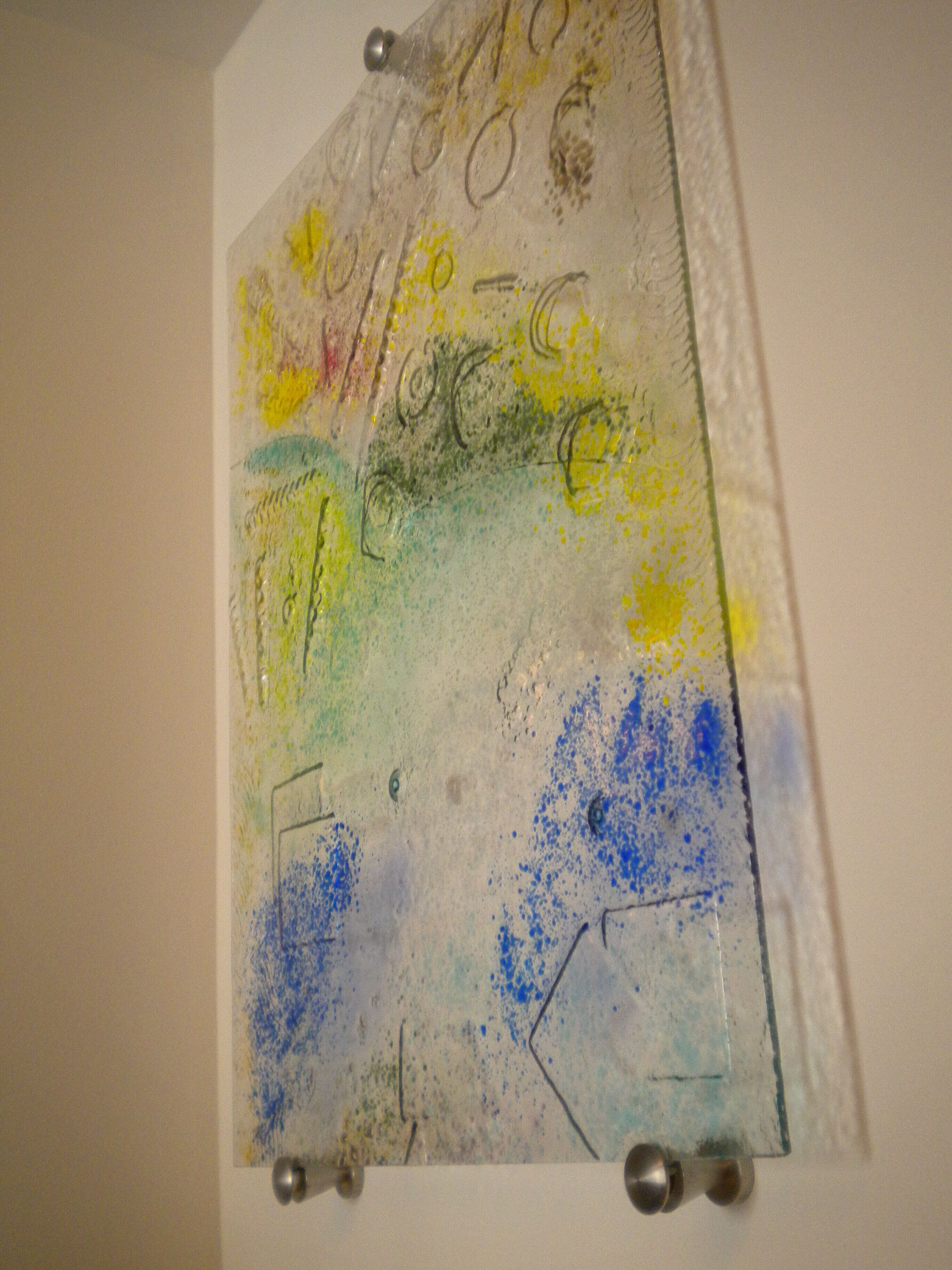 A wall with a textured artwork featuring abstract shapes and colors.