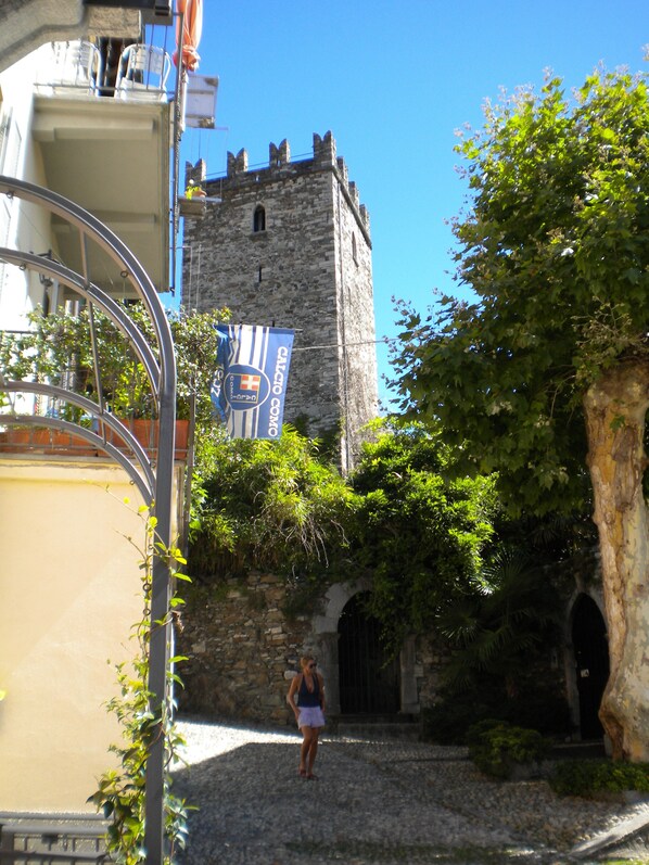 A cobblestone street leading to a historic stone tower with a flag.