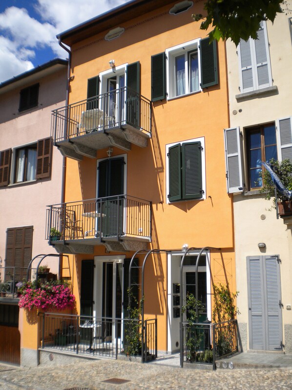 A multi-story building with balconies, a door, and a window with shutters.