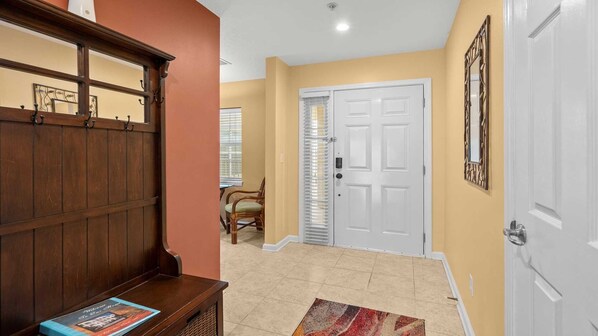 A hallway with a wooden bench, a door, and a chair.