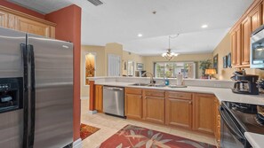 A modern kitchen with wooden cabinets, stainless steel appliances, and a large island with a sink.