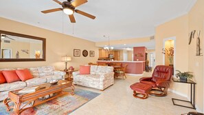 A spacious living room with a ceiling fan, a dining area, and a kitchen.