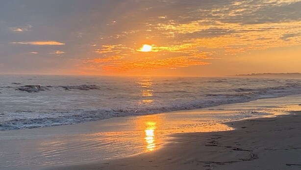 A beach with the sun setting over the horizon, reflecting on the wet sand. - Enjoy our new 16x25 screened in porch on Ocean Point Golf course (Fripp Island)
