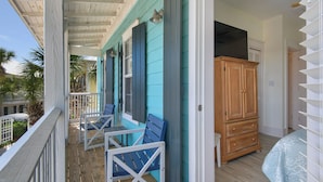 A balcony with wooden railings, a wooden cabinet, and a bed with a patterned bedspread. - Walk to a public beach! Walk to restaurants! True Owner Operator. (Santa Rosa Beach)