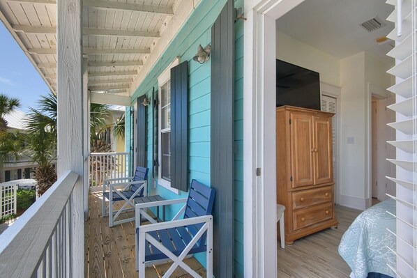 A balcony with wooden railings, a wooden cabinet, and a bed with a patterned bedspread.