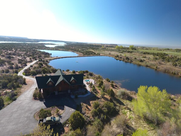 A lodge with a large swimming pool, surrounded by a natural landscape and a view of a lake. - Beautiful Lake-side 5 Bedroom Lodge (Altamont)