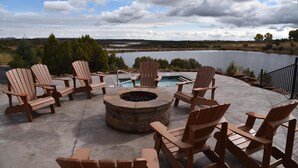 A patio area with Adirondack chairs, a fire pit, and a pool. - Beautiful Lake-side 5 Bedroom Lodge (Altamont)