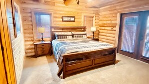 A log cabin bedroom with a large bed, two bedside tables, and a ceiling light. - Beautiful Lake-side 5 Bedroom Lodge (Altamont)