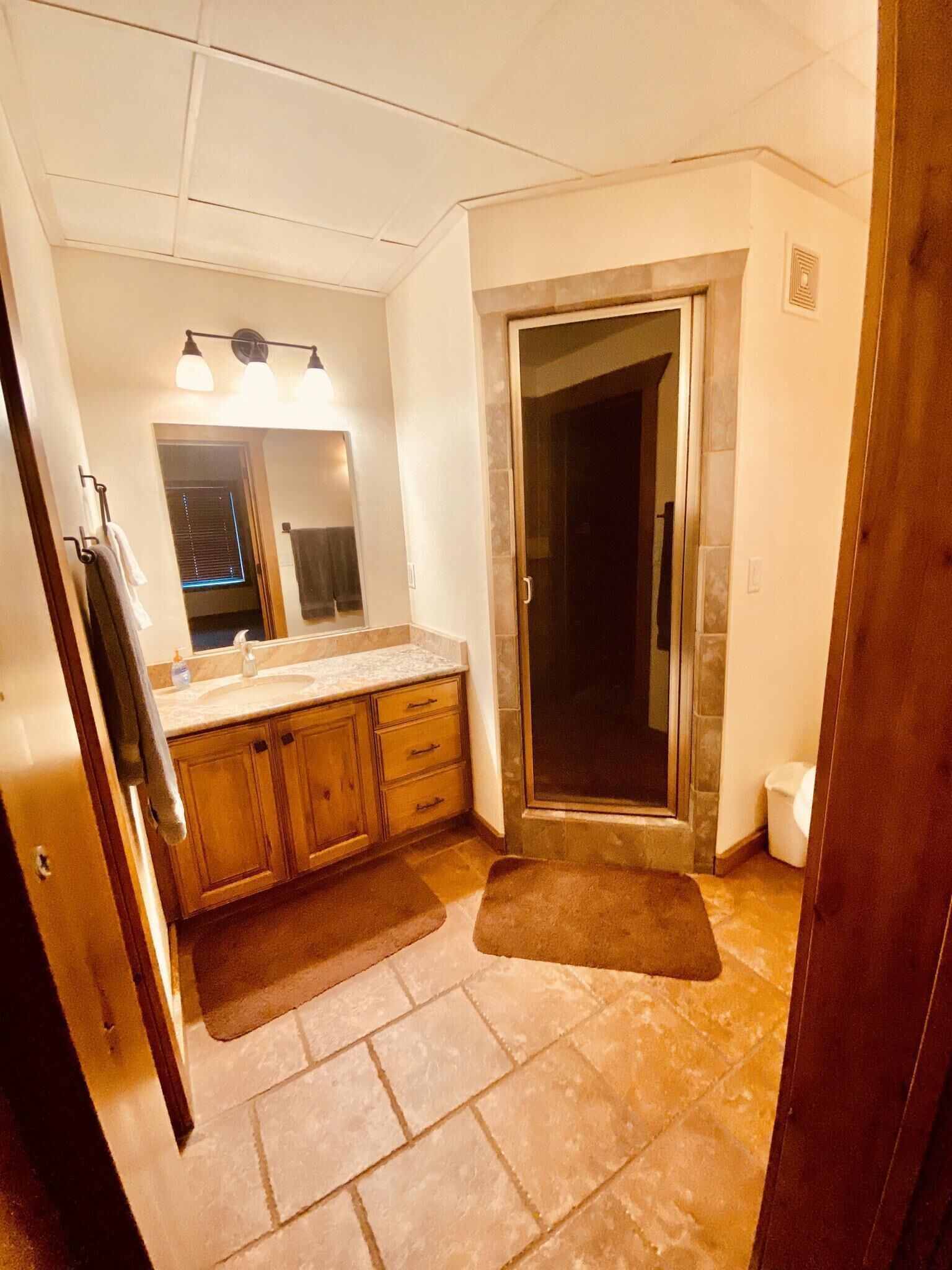 A bathroom with a shower, a sink, and a mirror.