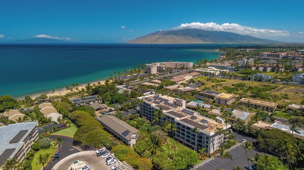 A coastal resort area with buildings, a beach, and a mountain in the background.