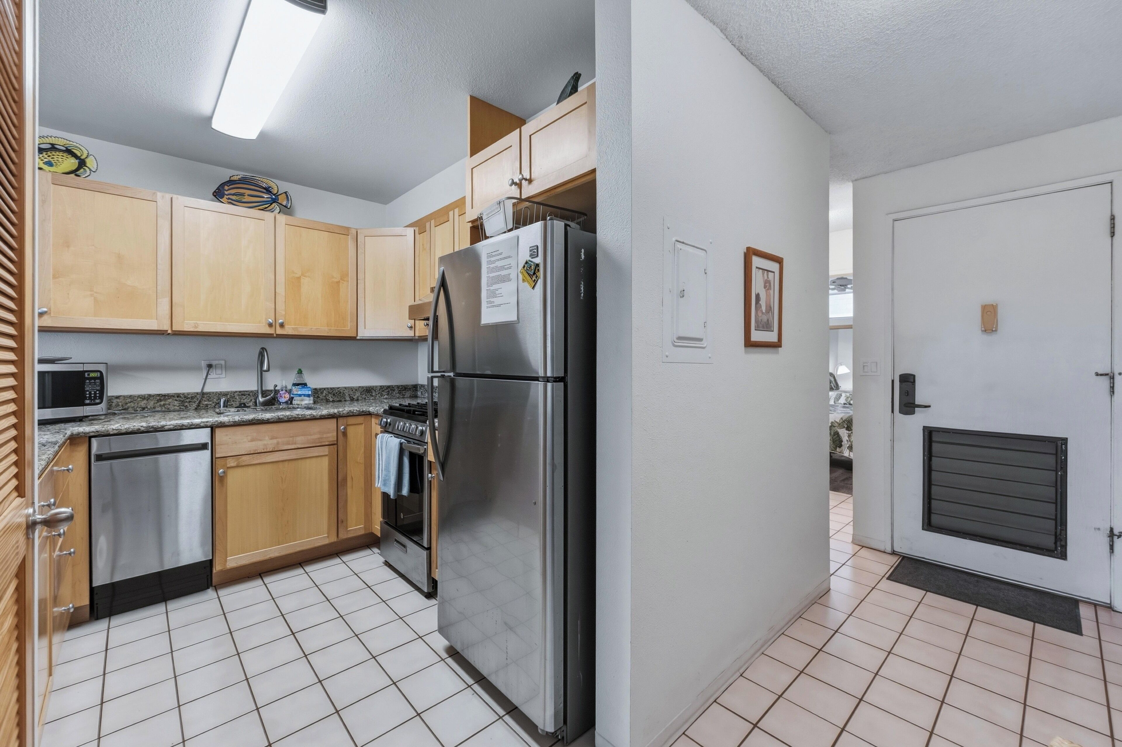 A kitchen with wooden cabinets, stainless steel appliances, and a tiled floor.