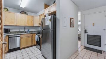 A kitchen with wooden cabinets, stainless steel appliances, and a tiled floor.