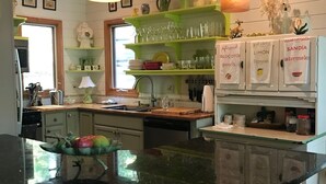 Uma cozinha com ilha central, armários de madeira e luminárias pendentes.