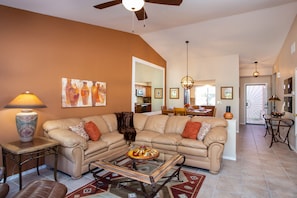 A living room with a beige sofa, a glass coffee table, and a lamp.
