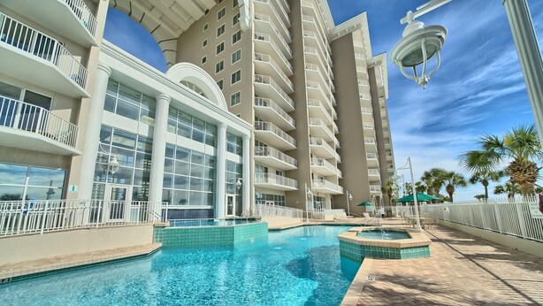 Un hotel con una grande piscina, diversi balconi e vista sull'oceano.