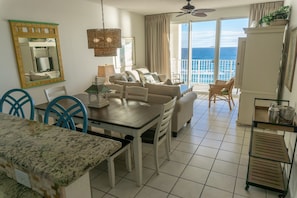 Relax in this spacious living area with a dining table, sofa, and balcony offering a view of the sea.