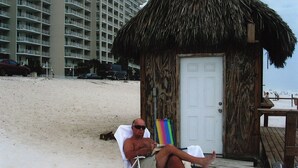 Una casetta sulla spiaggia con tetto di paglia, una porta in legno e un piccolo portico.
