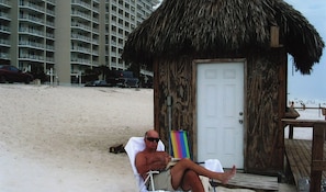 A beach hut with a thatched roof, a wooden door, and a small porch.