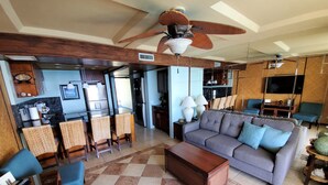 Ein geräumiger Wohnbereich mit einer Couch, Sesseln, einem Couchtisch und einem Deckenventilator.