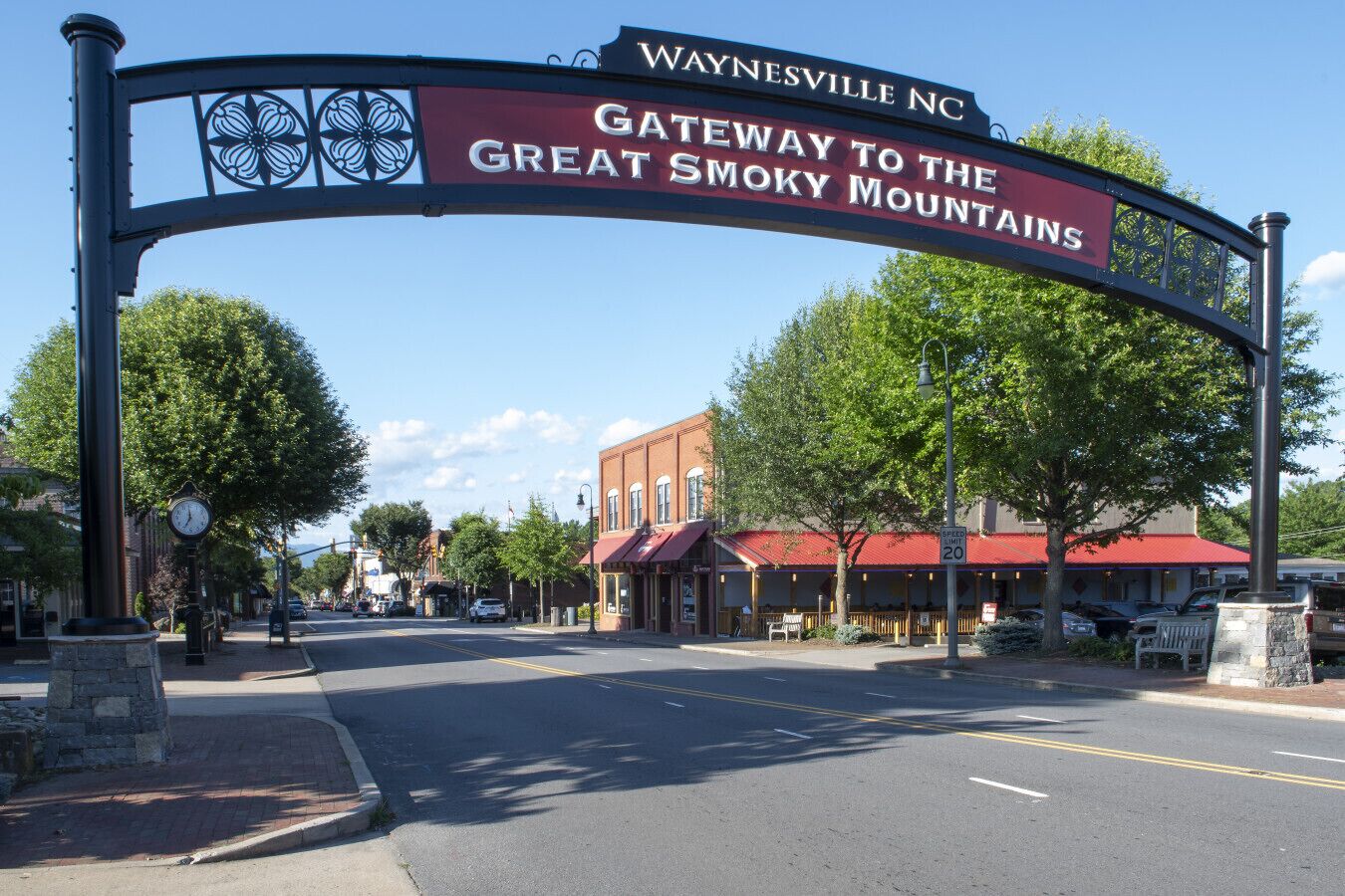 Una señal de calle con la inscripción 'WAYNESVILLE NC' y 'PUERTA DE ENTRADA A LAS MONTAÑAS ESMOKIES'.