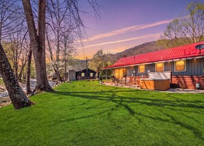 A hotel with a red roof, a covered outdoor area with seating, and a well-maintained lawn.