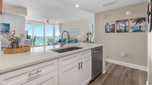 A modern kitchen with white cabinetry, a stainless steel sink, and a view to the outside.