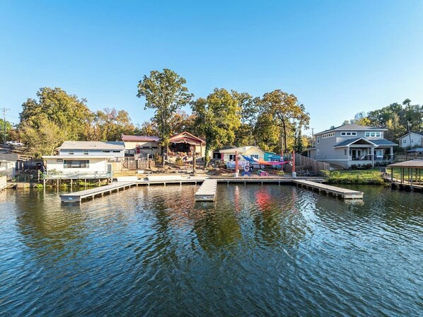 A waterfront property with a dock, a covered area, and a house with a large deck.