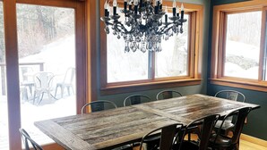 Un espace repas avec une table en bois, des chaises en métal et un lustre.