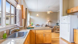 A kitchen with wooden cabinets, a stainless steel sink, a white refrigerator, and a ceiling fan.