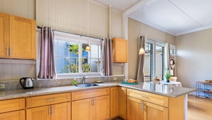 A kitchen with wooden cabinets, a granite countertop, a sink, and a window with curtains.