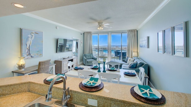 A modern kitchen with granite countertops, a built-in sink, and a dining area with a table and chairs.