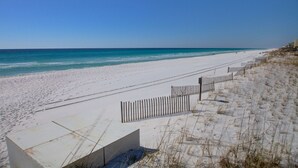A beach with white sand and a wooden fence.