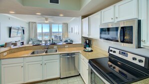 A modern kitchen with white cabinets, a stainless steel dishwasher, a double oven, and a microwave.