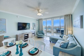 Relax in a spacious living area with a flat-screen TV, dining table, and comfortable seating near a large window offering a city view.