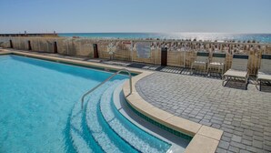 A swimming pool with a clear view of the ocean, a no diving sign, and a seating area with chairs.