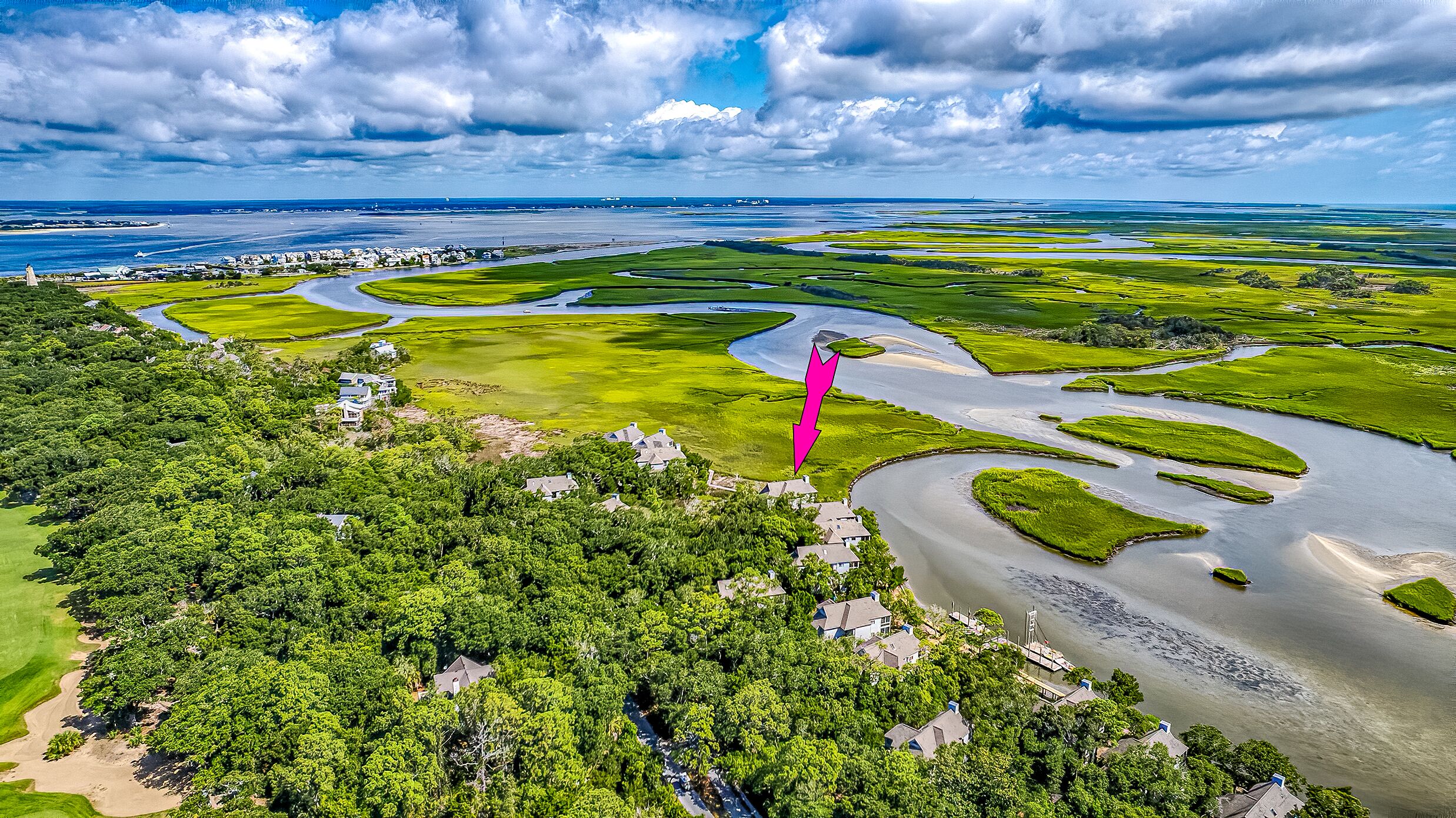 An aerial view of a coastal area with green fields, water bodies, and residential buildings.