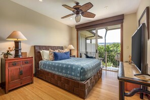 Ein Schlafzimmer mit einem hölzernen Bett, einem Deckenventilator, einem Fernseher und einem Balkon mit Blick.