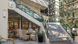 Un vestíbulo de hotel con una escalera, muebles de mimbre y una planta en maceta.