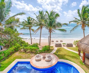 Un espace piscine doté d’un jacuzzi, de chaises longues et offrant une vue sur la plage et l’océan.