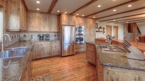 A spacious kitchen with wooden cabinets, stainless steel appliances, and a granite countertop.