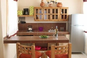 Compact kitchen with a wooden table and chairs, featuring a refrigerator, cabinet, and coffee maker.