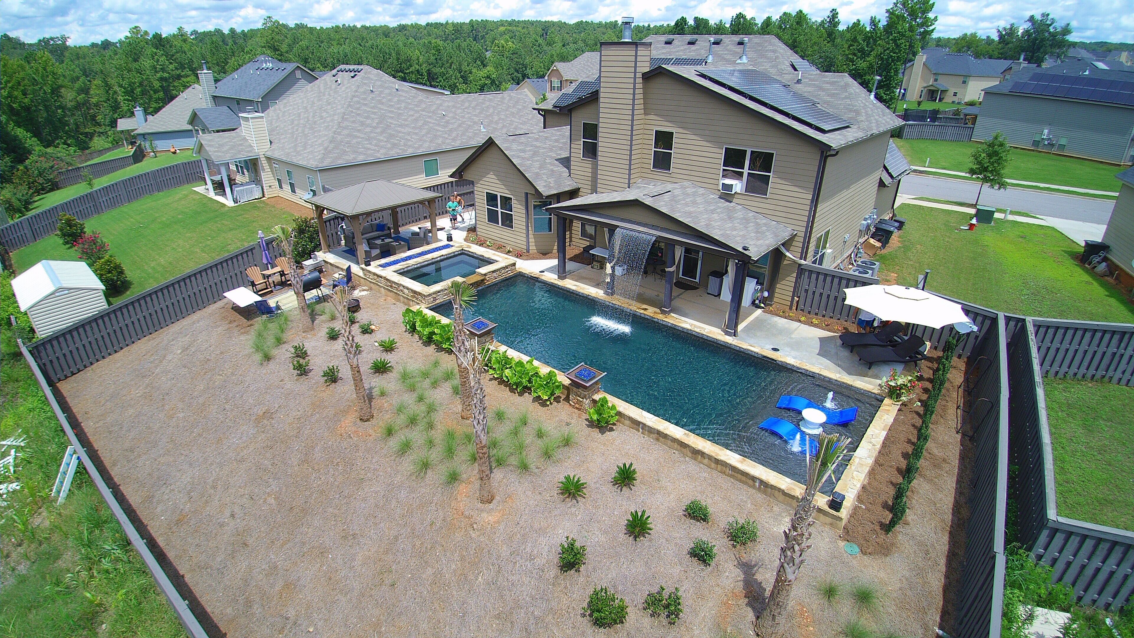 A residential property with a large backyard featuring a swimming pool, outdoor seating, and a covered patio area. - Year round rental 4 miles from the Augusta National pool Hot tub Gym tanning bed (North Augusta)