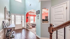 A hallway with wooden flooring, a white door, and a staircase with a wooden handrail. - Year round rental 4 miles from the Augusta National pool Hot tub Gym tanning bed (North Augusta)