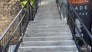 Eine Treppe führt zu einem Gebäude, an dem ein Schild mit der Aufschrift ‚MADE COFFEE‘ steht.