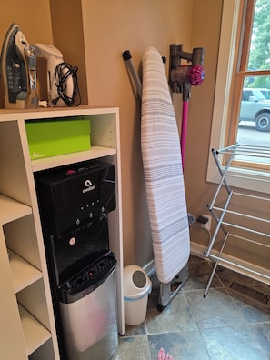 Un espace dédié à la lessive, équipé d’une planche à repasser, d’un lave-linge et d’un étendoir.
